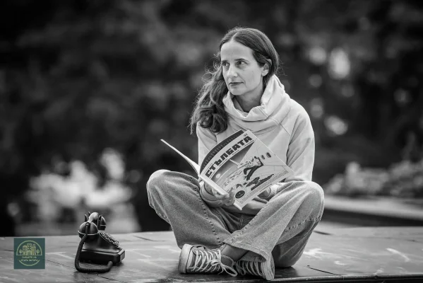 Черно-бял портрет на Райна Димитрова, седнала с отворено списание и телефон до нея.