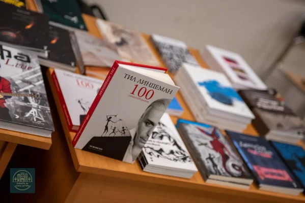 Близък план на книги, подредени върху дървен щанд, с част от кориците изправени.