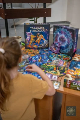 Дете играе настолна игра на щанд с книги и цветни кутии.